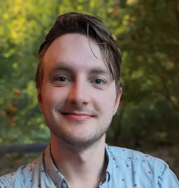 Christian Merkovsky in blue shirt with trees in background
